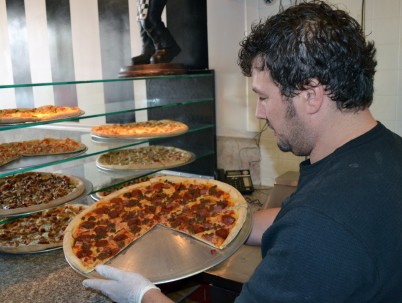 Tony Khal sets out a pizza as opening day for I Love New York Pizza’s already  seen customers.  Photo Credit: Valeriya Ponomarova